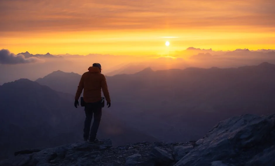 A lone hiker silhouetted against a mountain sunrise after a long walk